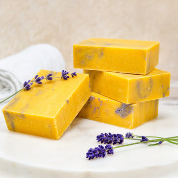 Poofy Organics Lavender Lemon soap bars stacked with fresh lavender sprigs