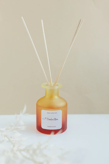 Timeless Organics Desert Rose reed diffuser beside dried flowers