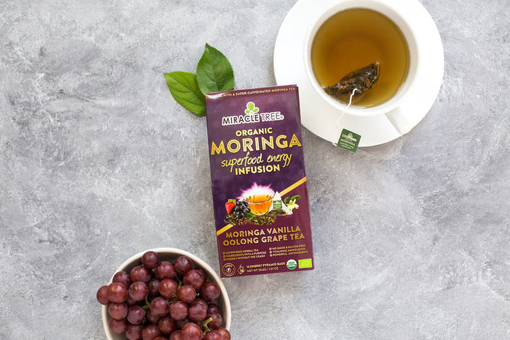 Vanilla Oolong Grape moringa energy tea box with grapes and a cup of tea.