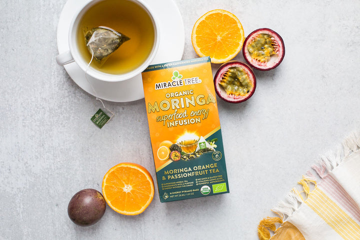 Orange Passionfruit moringa energy tea box with oranges, passionfruit and a cup of tea.