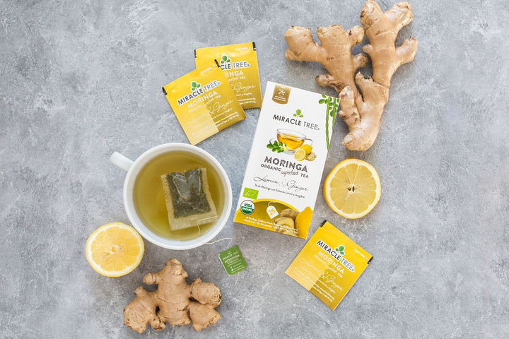 Lemon & Ginger moringa tea box with lemon, ginger root and a cup of tea.