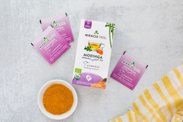 Turmeric moringa tea box with sachets and a small bowl of turmeric.